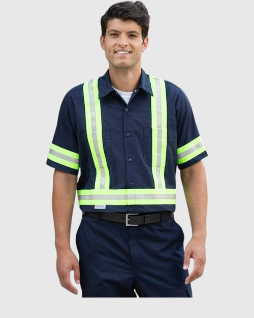 A man wearing a navy blue short-sleeve work shirt with high-visibility neon yellow-green reflective stripes, paired with navy pants and a black belt, against a light gray background.