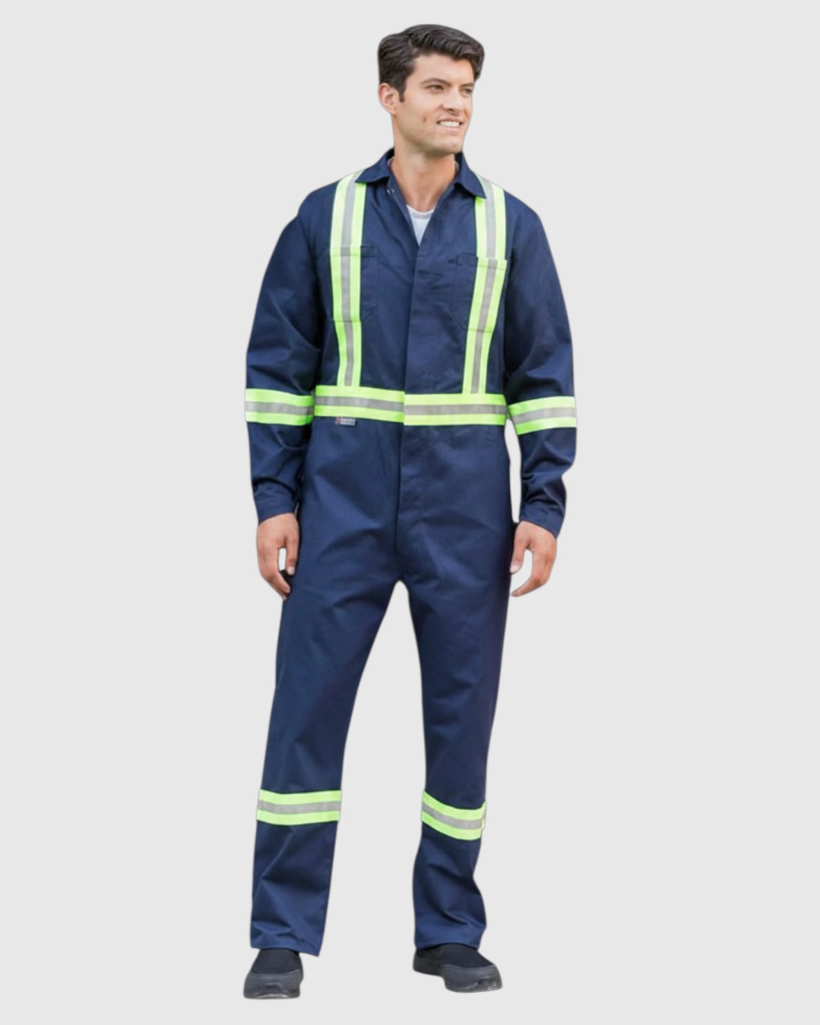 A man wearing a navy blue high-visibility work jumpsuit with bright yellow-green reflective stripes, standing against a light gray background.