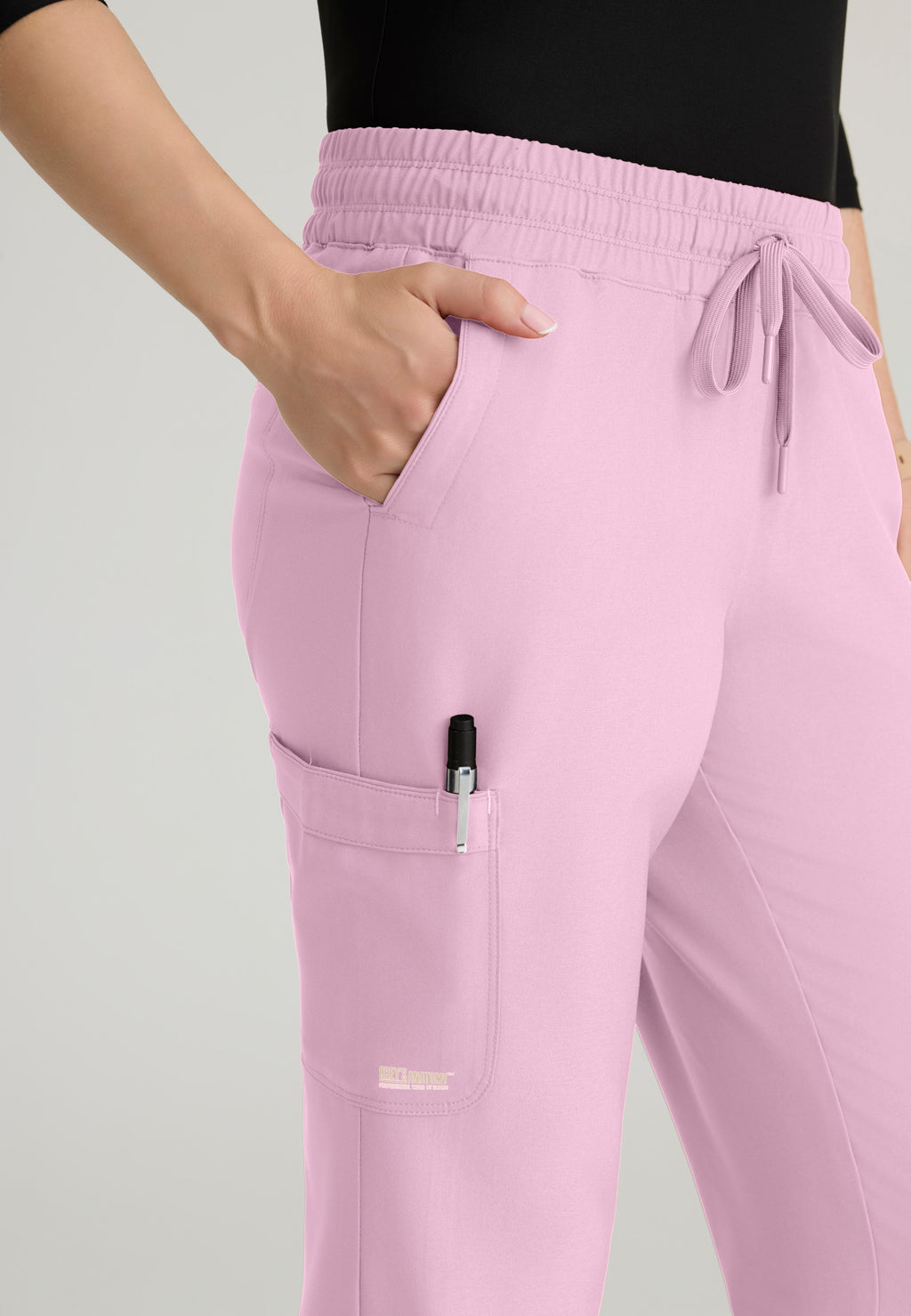 Close up view of the Grey's Anatomy Evolve women's Terra scrub jogger in the colour Misty Pink.