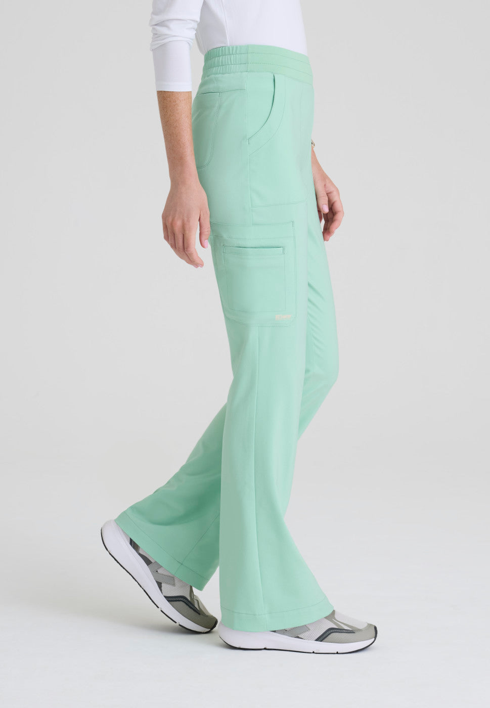 Side view of the GSSP729 Grey's Anatomy Evolve Sky Fit and Flare Scrub pant in the colour Soft Melon.
