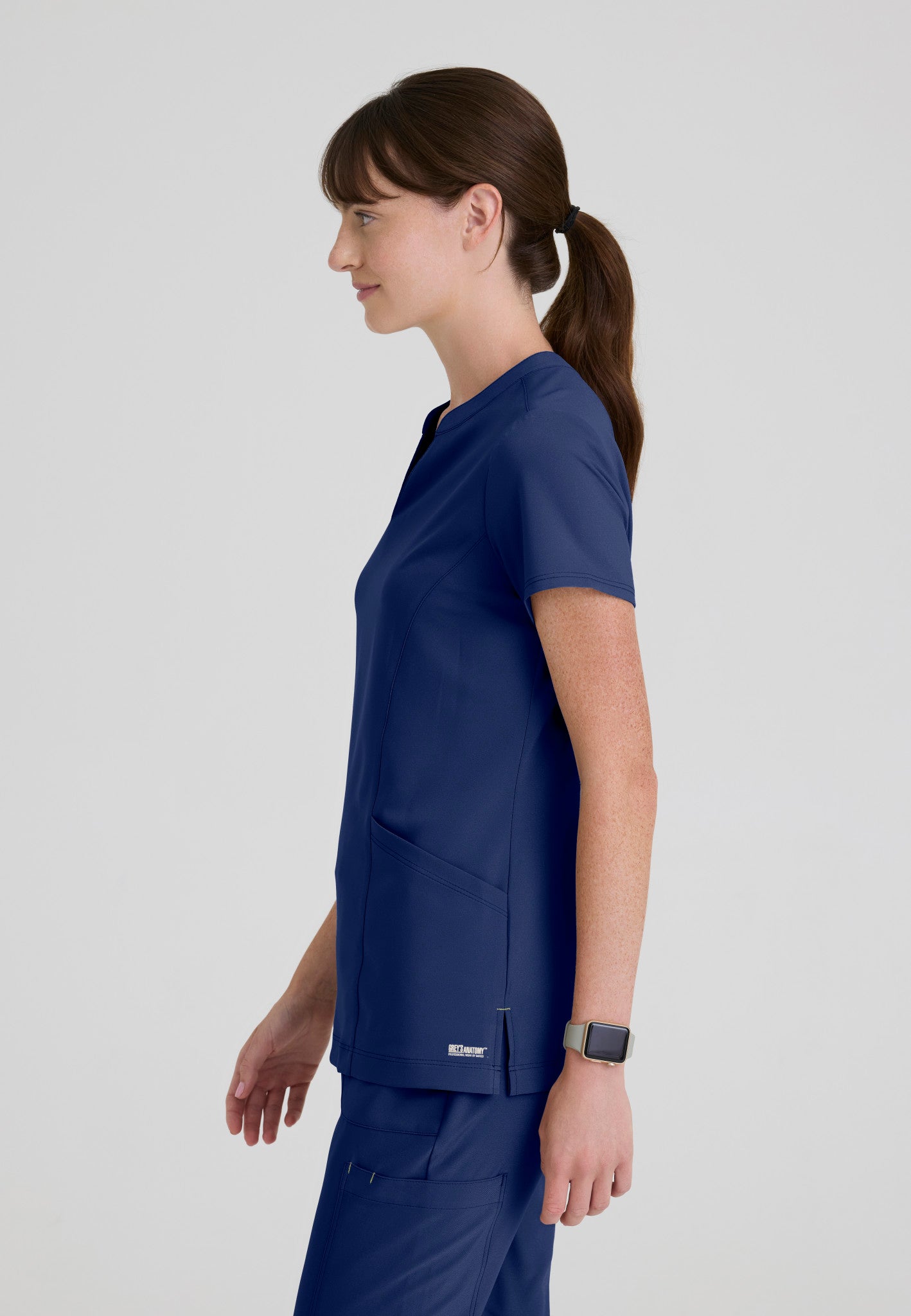 Side view of the Grey's Anatomy Evolve women's Sky scrub top in the colour Indigo.