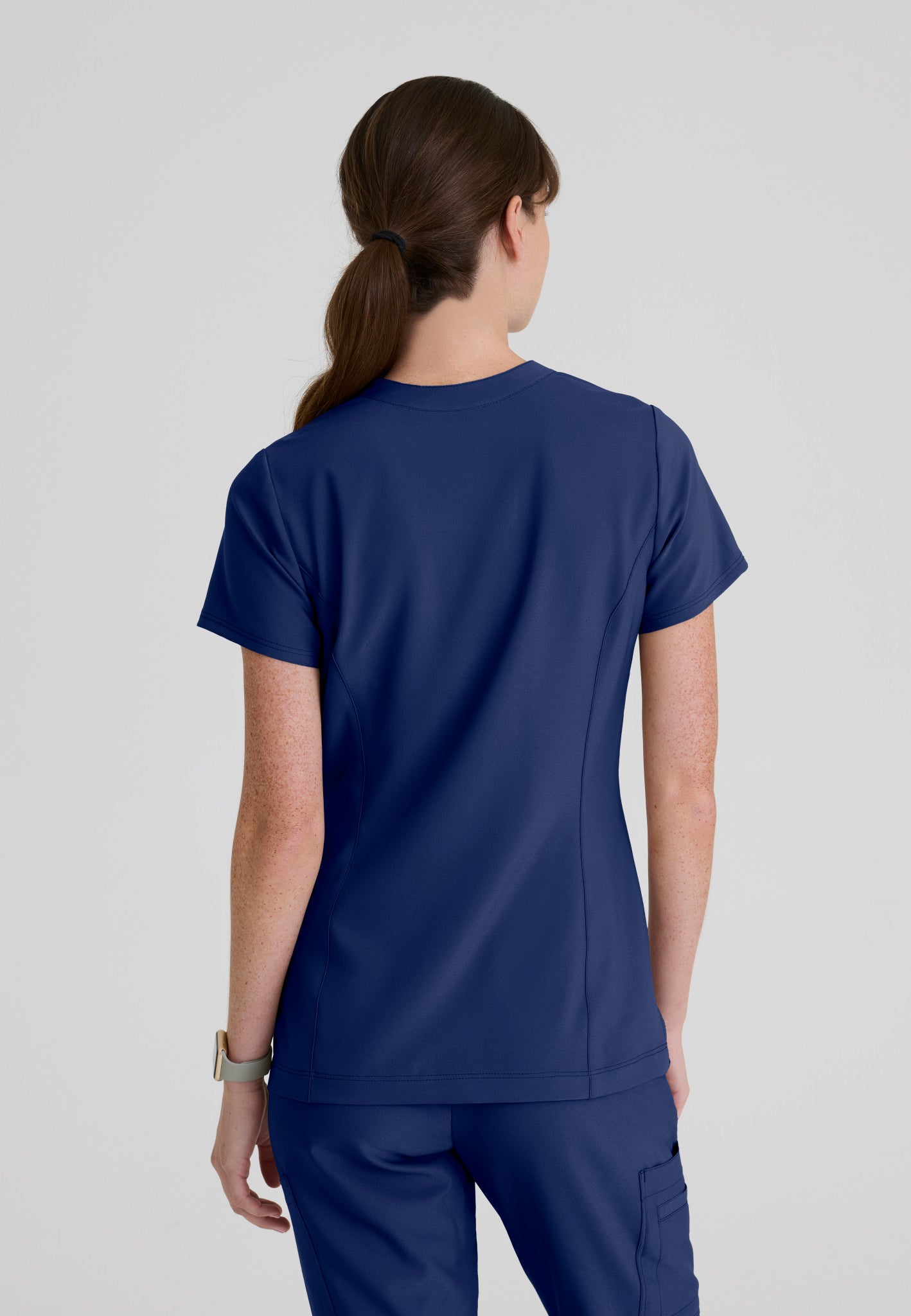 Back view of the Grey's Anatomy Evolve women's Sky scrub top in the colour Indigo.