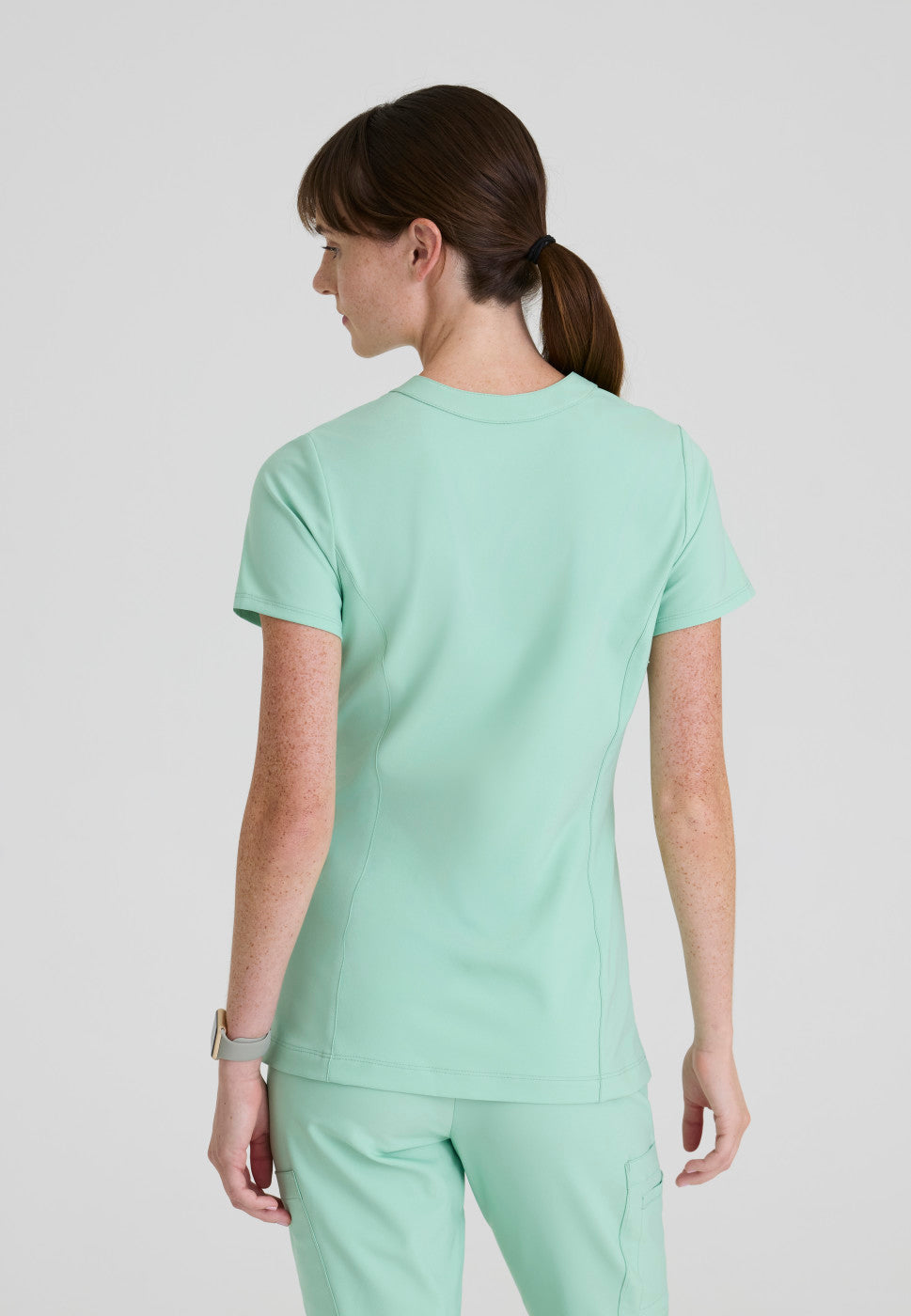 Back view of the GSST298 Grey's Anatomy Evolve Sky Banded Scrub Top in the colour Soft Melon.