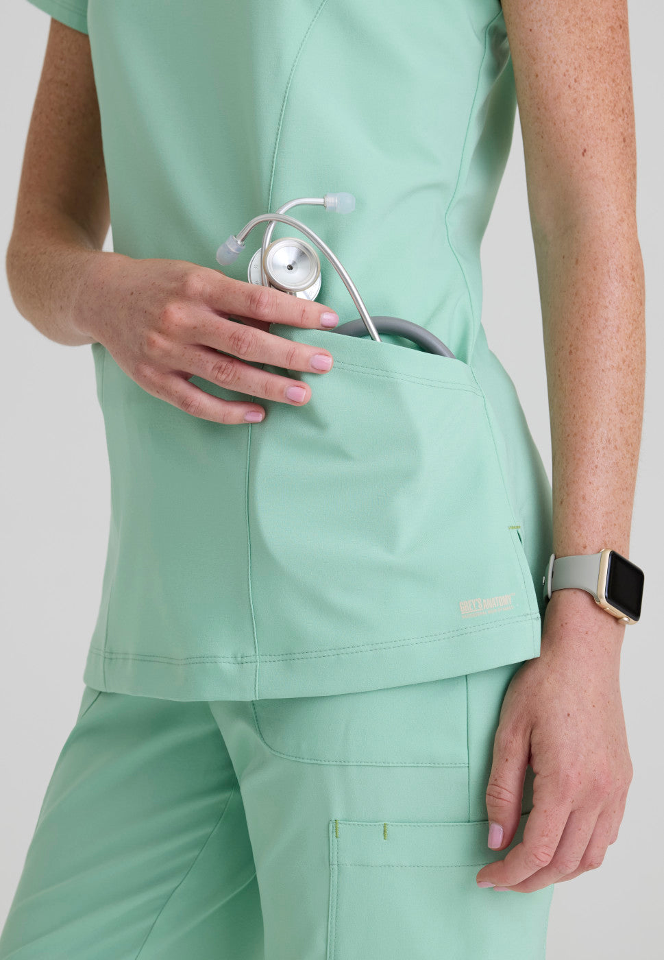 Close up view of the GSST298 Grey's Anatomy Evolve Sky Banded Scrub Top in the colour Soft Melon.