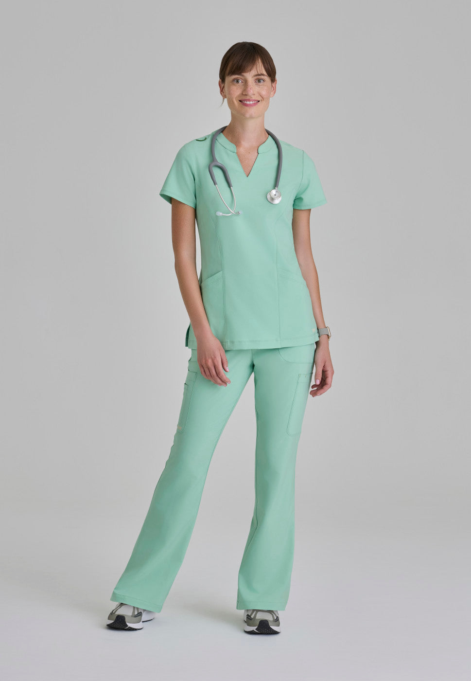 Full view of the GSSP729 Grey's Anatomy Evolve Sky Fit and Flare Scrub pant in the colour Soft Melon.