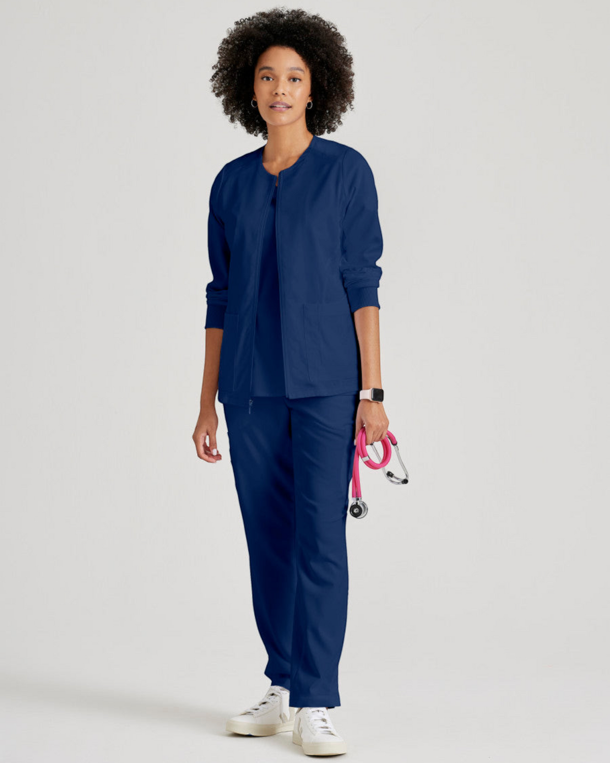 Lasalle Uniform Gianna warm-up scrub jacket in navy blue with a zip-front, worn by a model with a stethoscope.