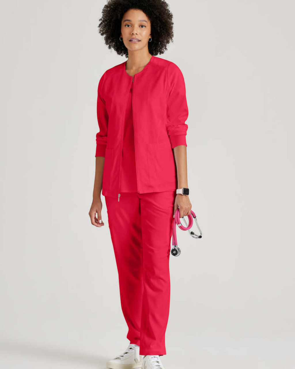 Model wearing Lasalle Uniform Grey's Anatomy by Barco Gianna warm-up scrub jacket in bright pink with matching scrubs.