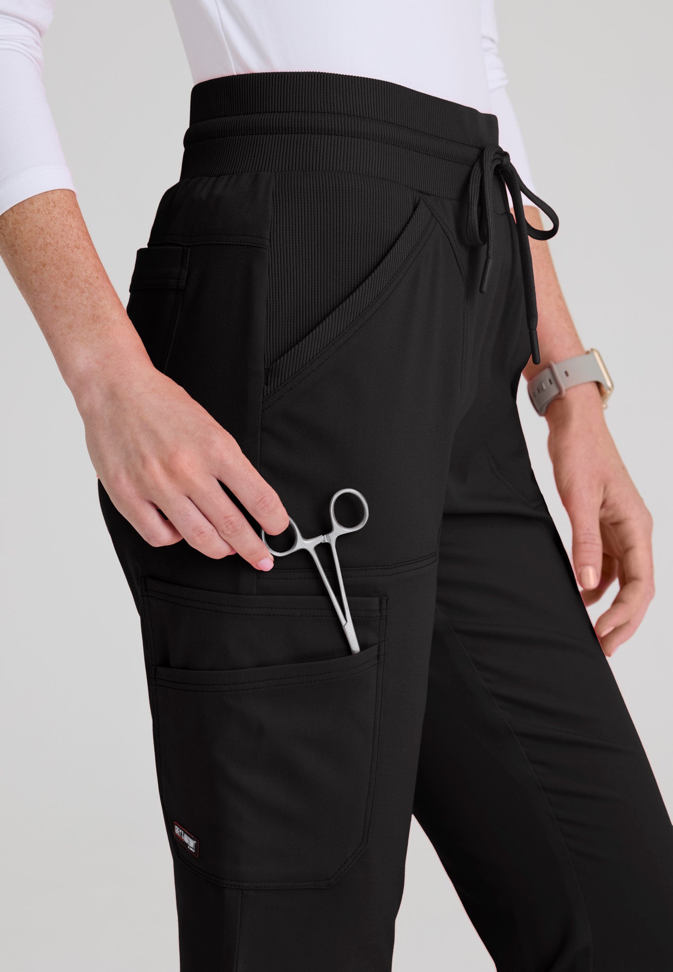 Close-up detail of smooth rib-knit yoga waistband and rib-trim slant pockets on the Kristi medical scrub pant. Black colour.