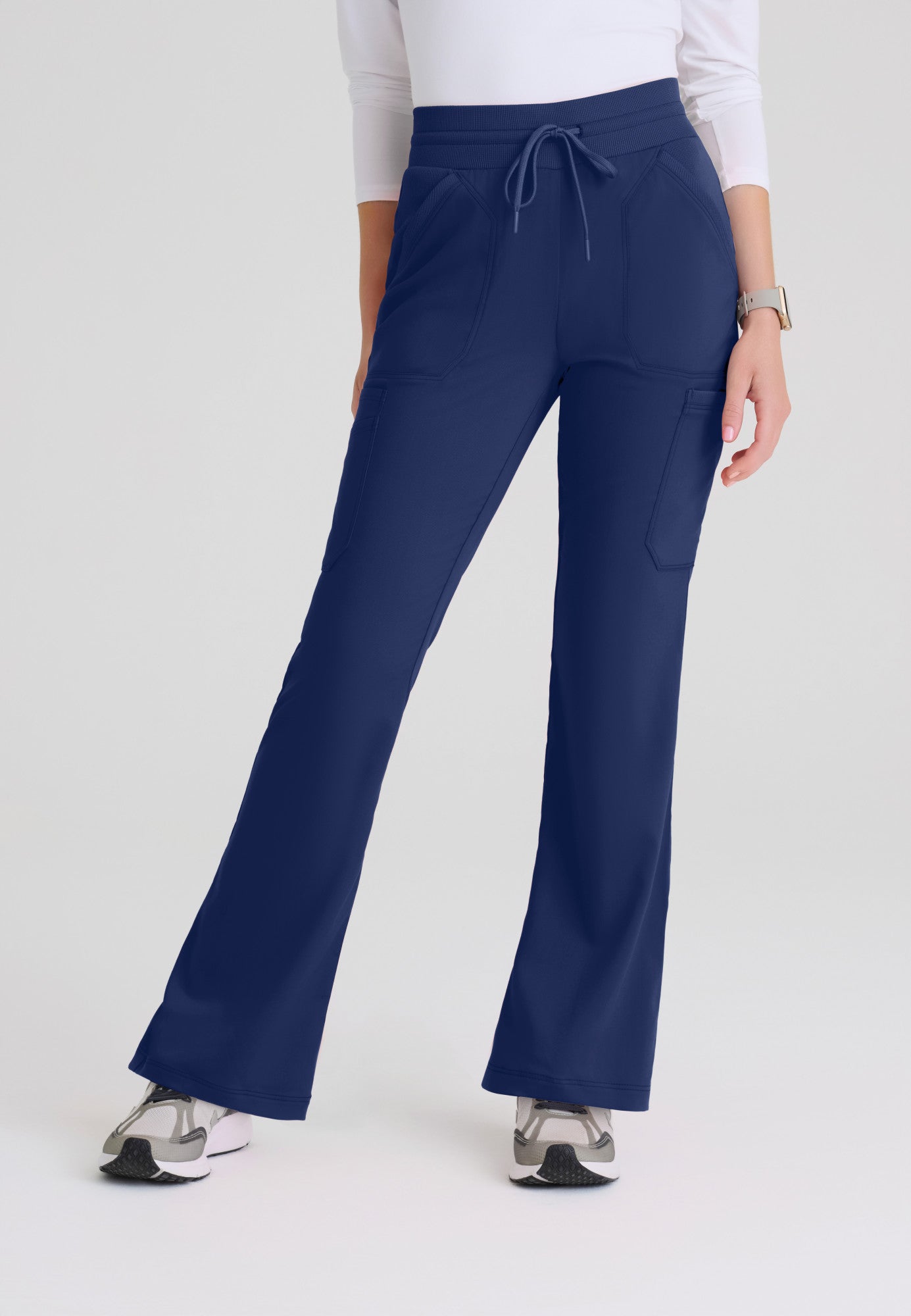 Front view of Kristi women's high-rise scrub pant featuring a fit & flare leg, knit waistband, and 7-pocket design. Indigo colour.