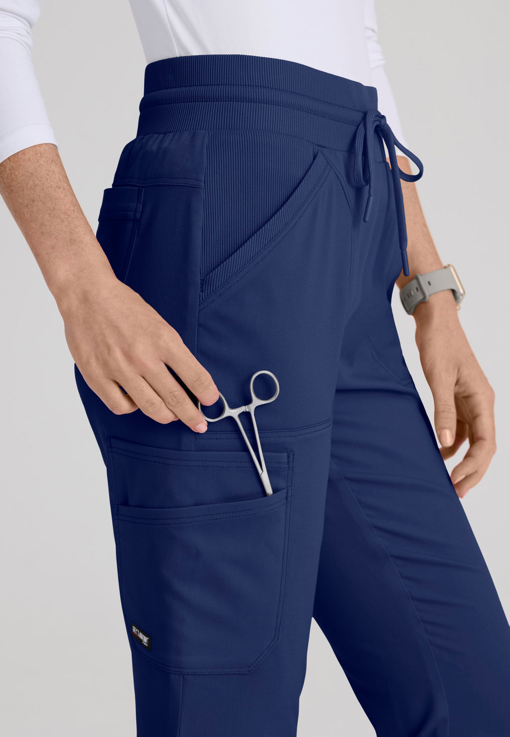 Close-up detail of smooth rib-knit yoga waistband and rib-trim slant pockets on the Kristi medical scrub pant. Indigo colour.