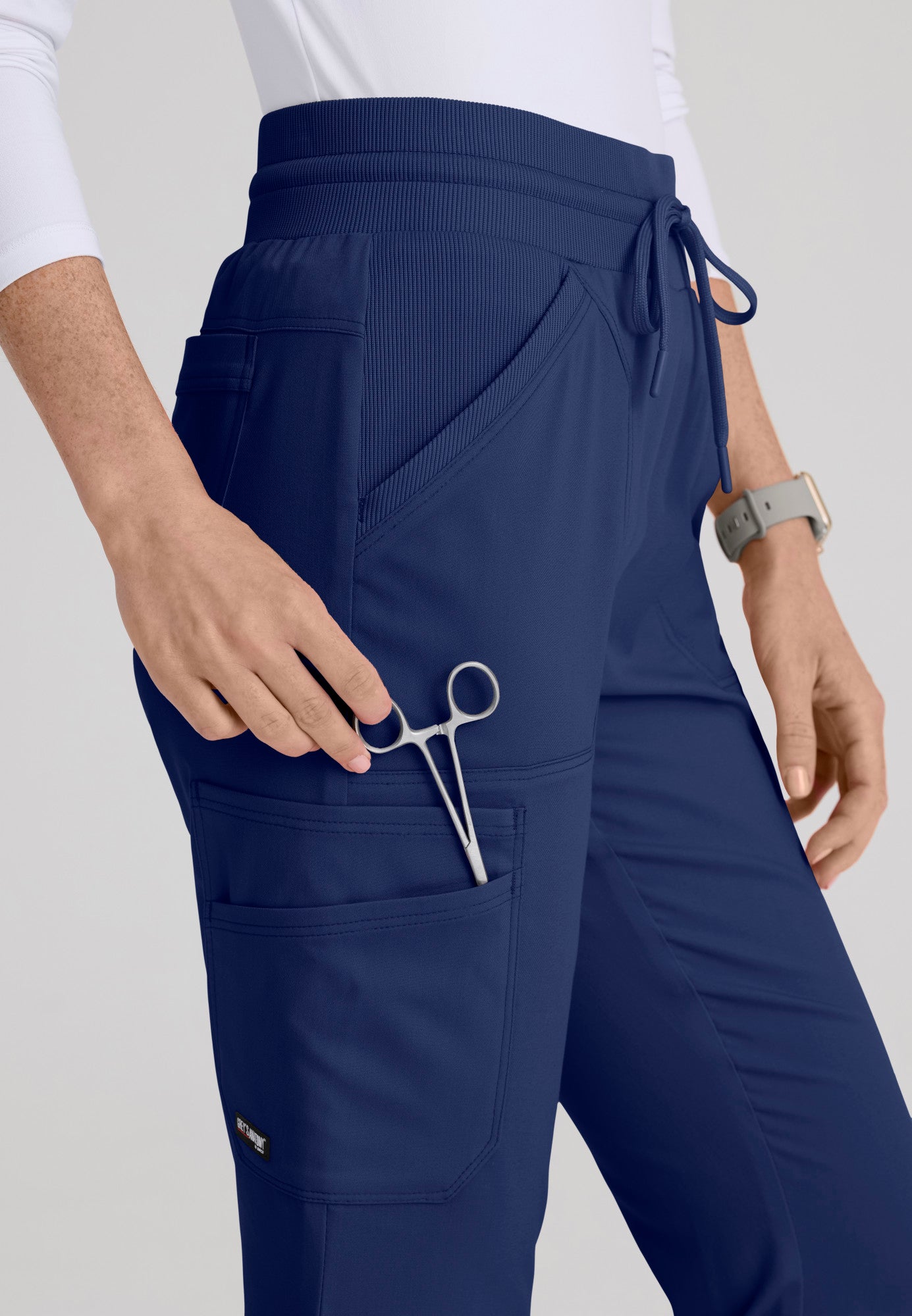 Close-up detail of smooth rib-knit yoga waistband and rib-trim slant pockets on the Kristi medical scrub pant. Indigo colour.