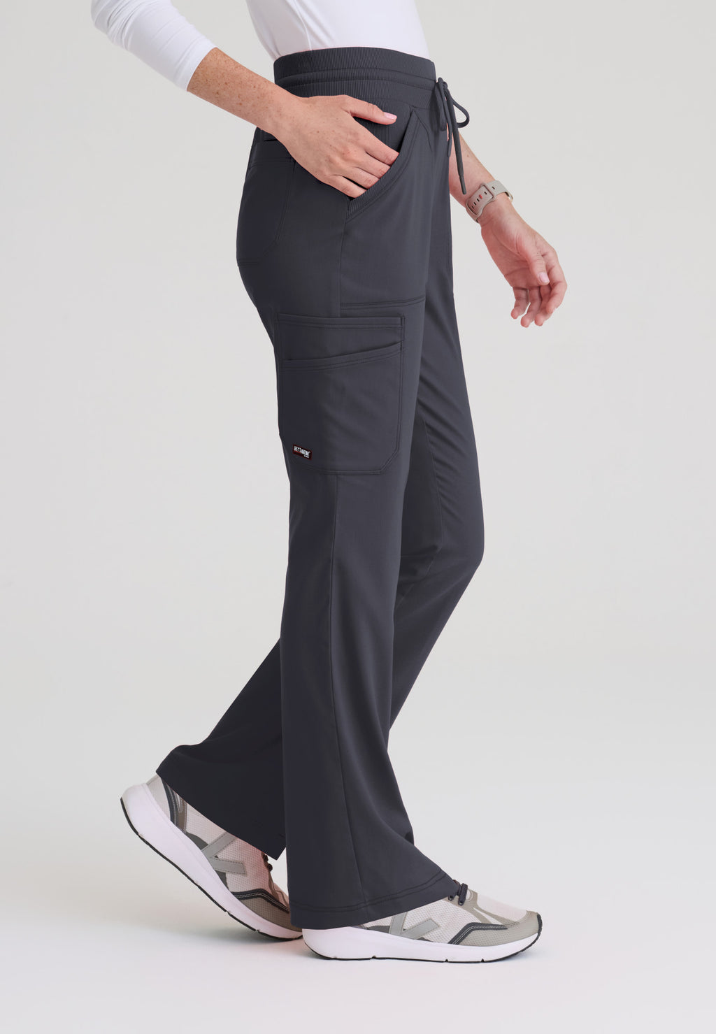 Side view of Kristi scrub pant showing deep cargo pockets and flared leg silhouette on soft stretch fabric. Steel colour.