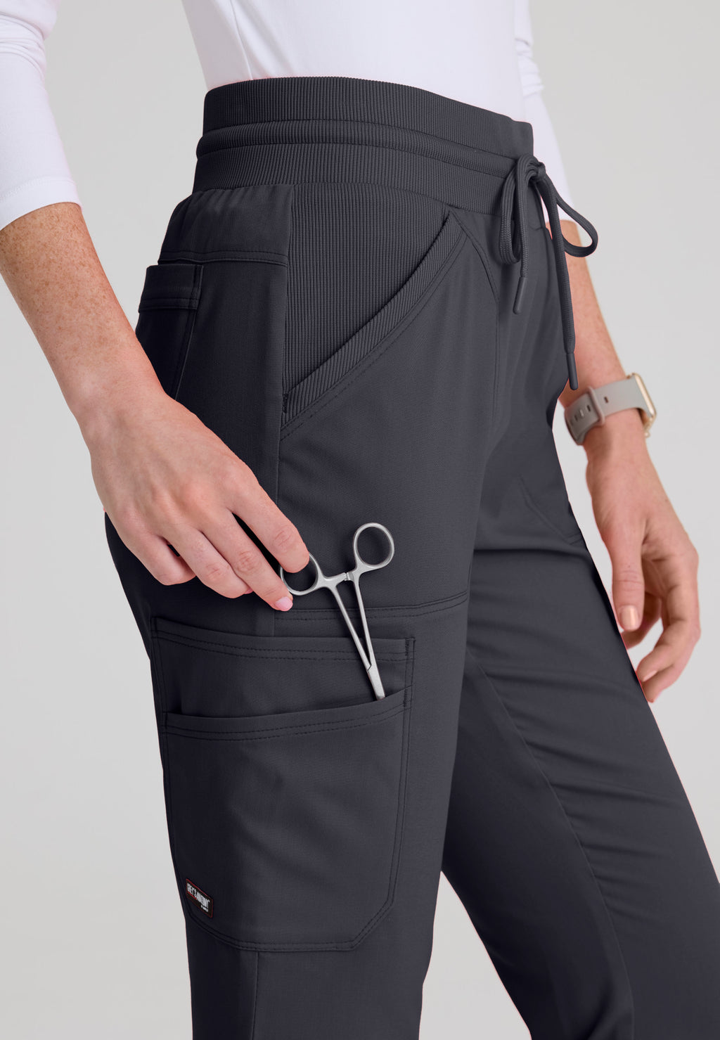 Close-up detail of smooth rib-knit yoga waistband and rib-trim slant pockets on the Kristi medical scrub pant. Steel colour.
