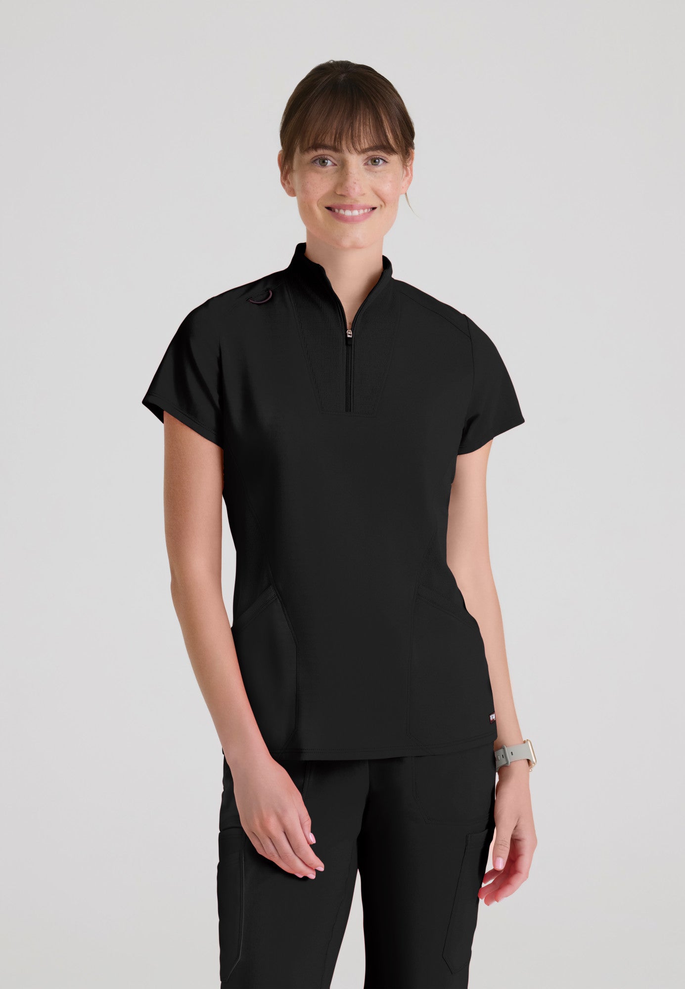 Front view of Grey's Anatomy Kristi scrub top featuring a modern convertible zip neckline, two discrete pockets, and a tailored fit.  Black colour.
