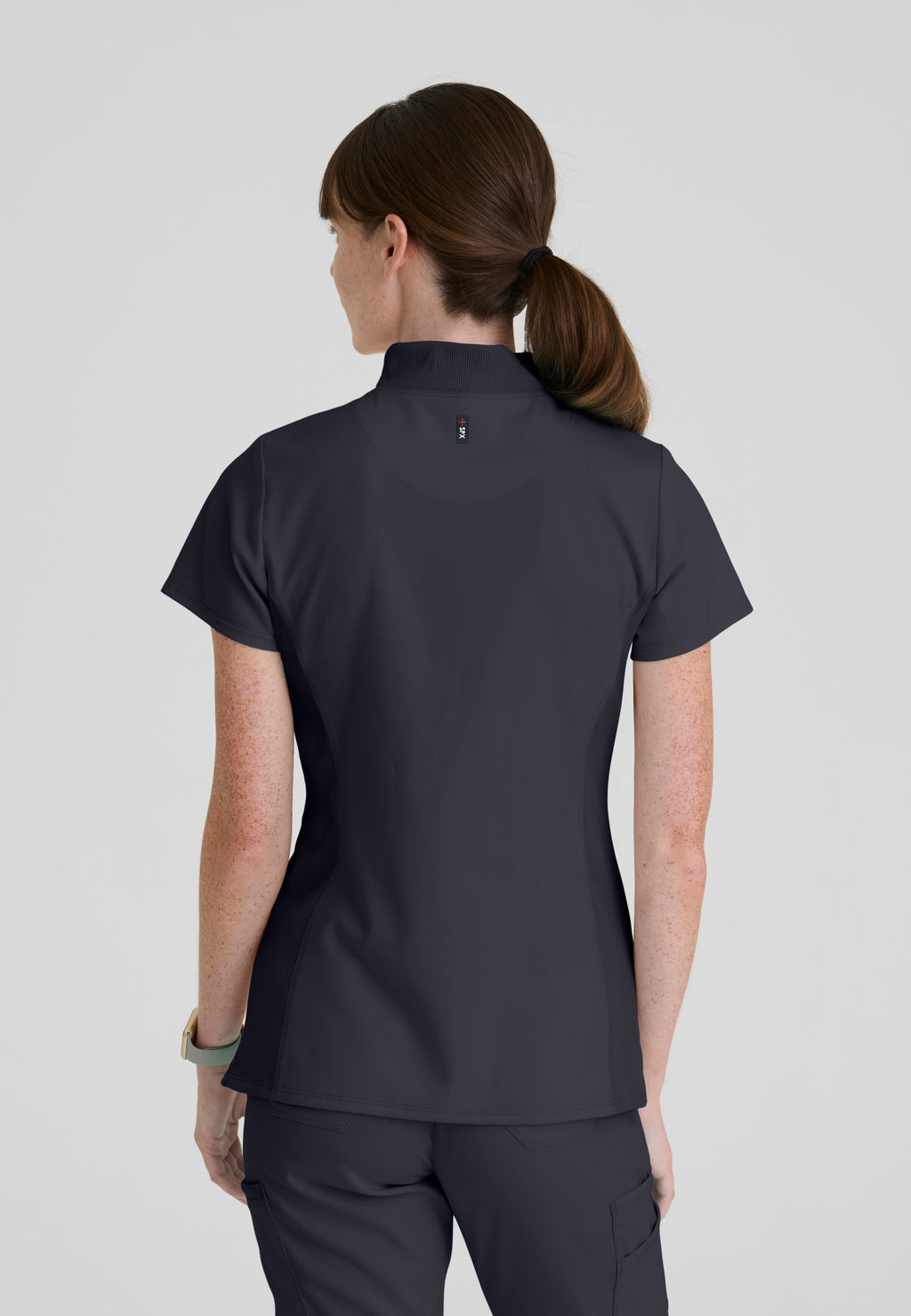 Back view of Grey's Anatomy Kristi scrub top highlighting the curved high-low hemline that provides added coverage while bending. Steel colour.