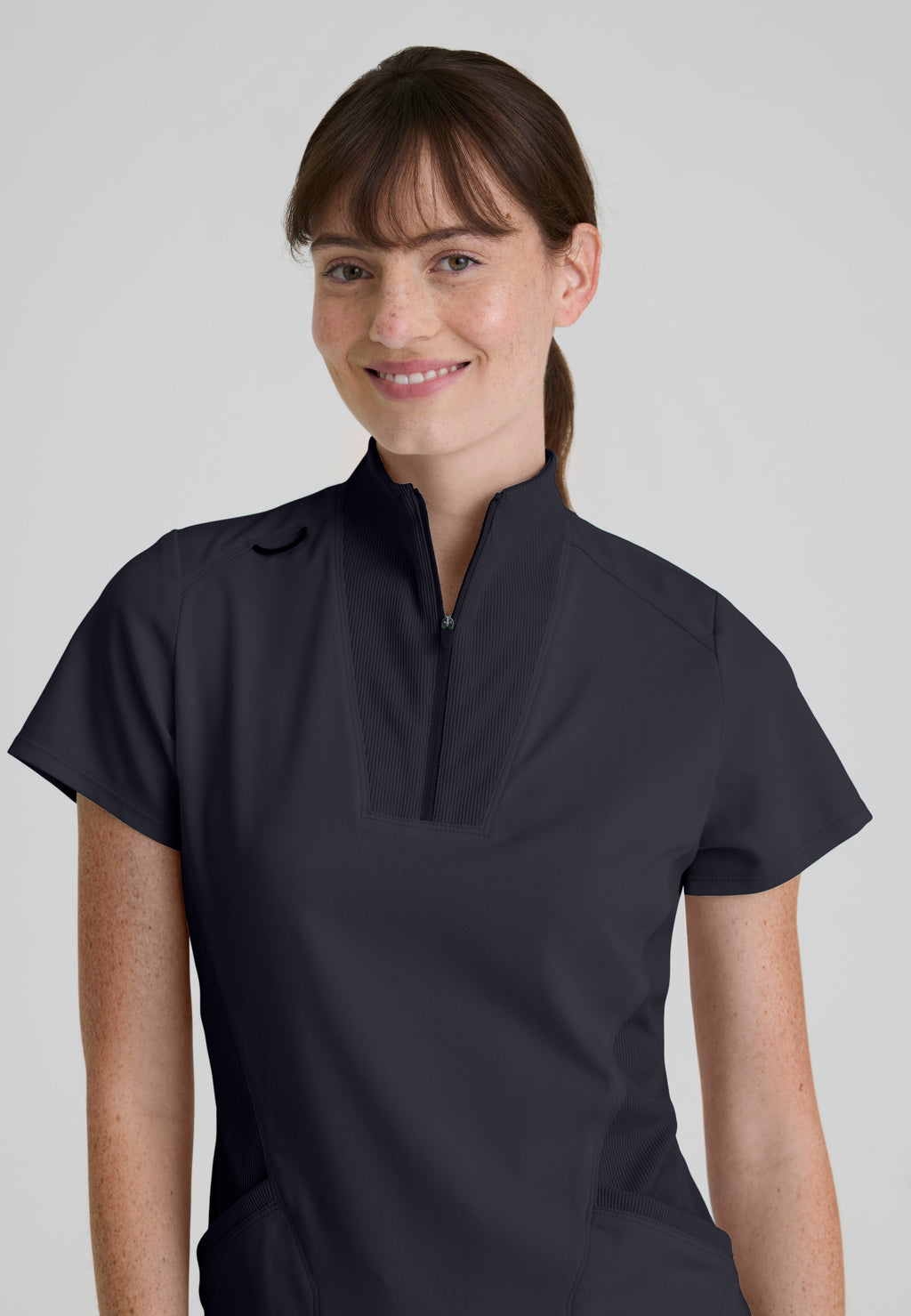 Close-up detail of the Grey's Anatomy Kristi scrub top with a sleek zipper and rib-knit collar placket on soft antimicrobial fabric. Steel colour.