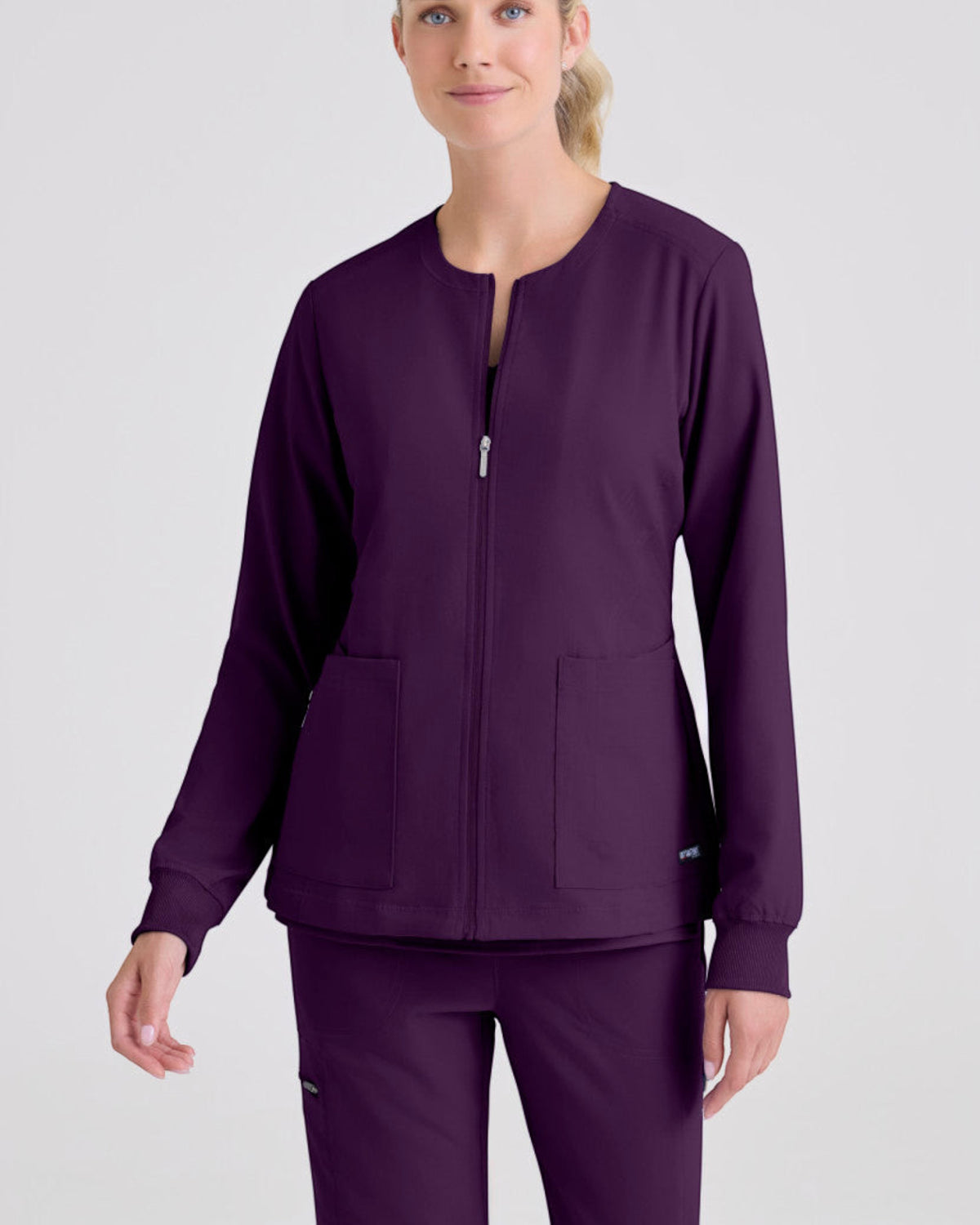 Lasalle Uniform Gianna warm-up scrub jacket in deep purple with a round neckline, full zip front, and rib-knit cuffs.