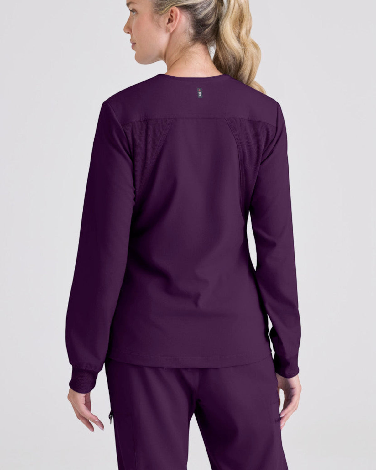 Lasalle Uniform Gianna warm-up scrub jacket in deep purple with long sleeves and rib-knit cuffs, back view.
