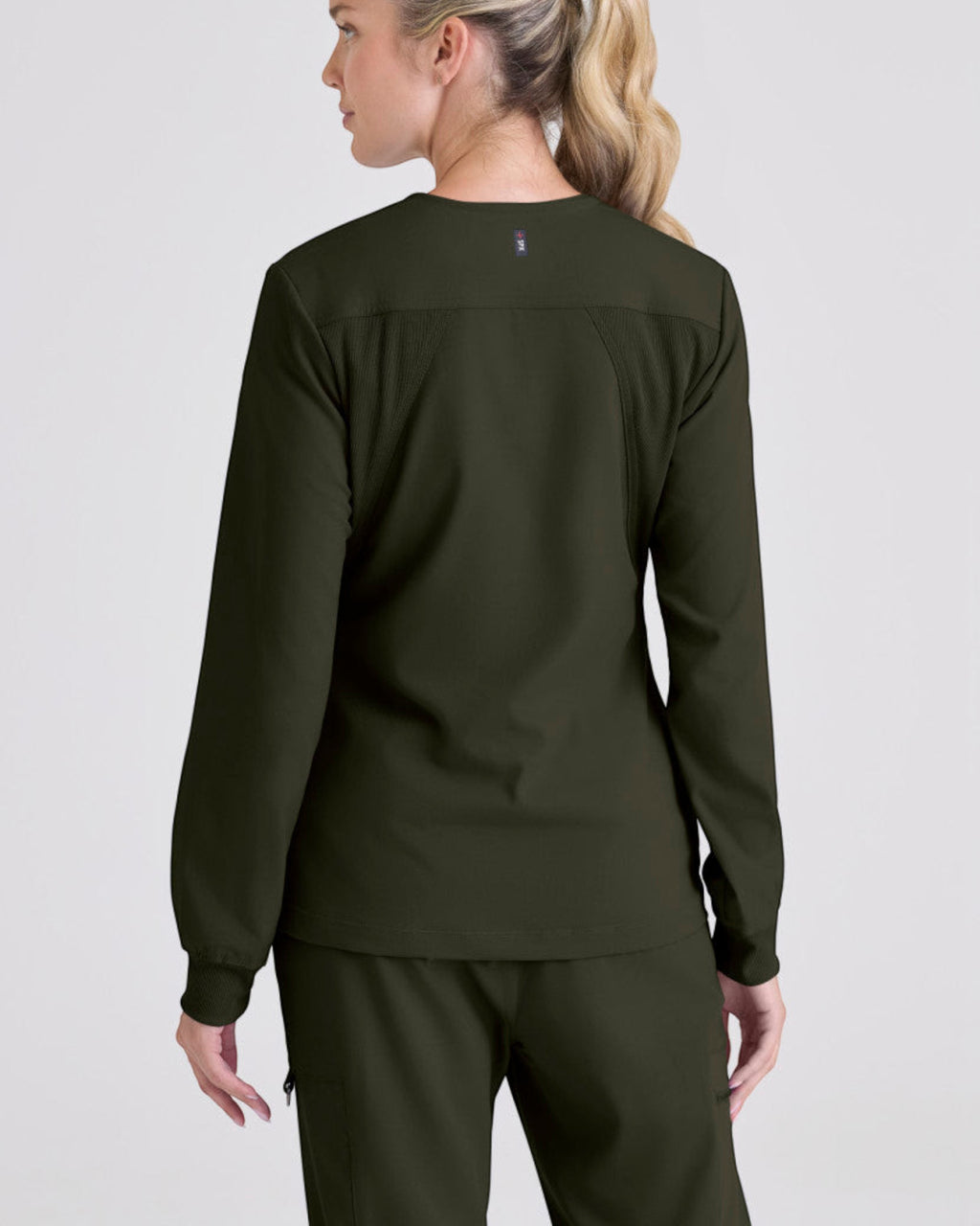 Back view of a woman wearing a dark olive Grey's Anatomy by Barco Gianna scrub jacket from Lasalle Uniform