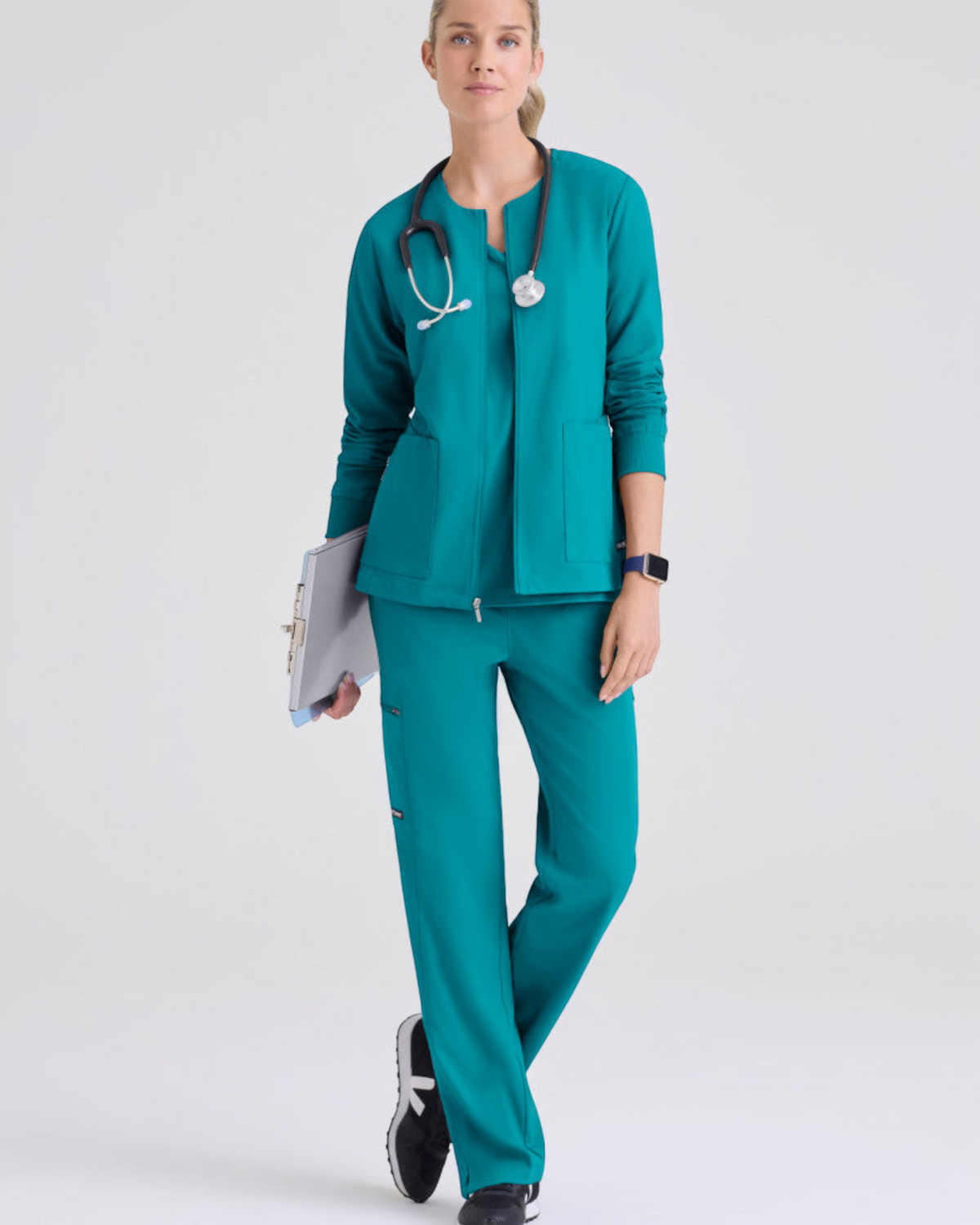 Lasalle Uniform model wearing a teal Gianna warm-up scrub jacket with a zip-front, rib-knit cuffs, and stethoscope.
