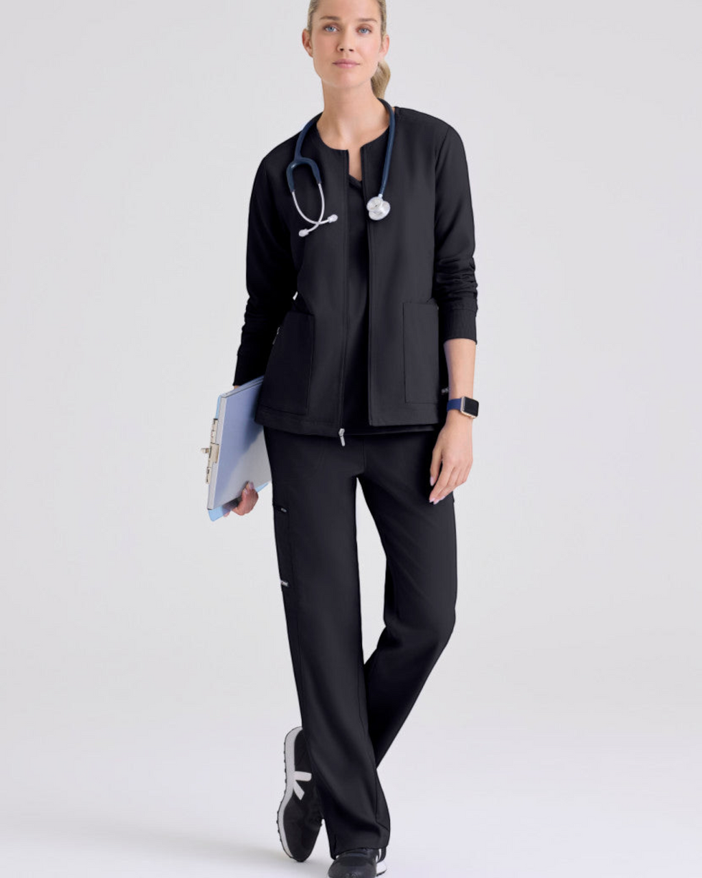 Lasalle Uniform model wearing a black Gianna warm-up scrub jacket with a zip front, rib-knit cuffs, and pockets.