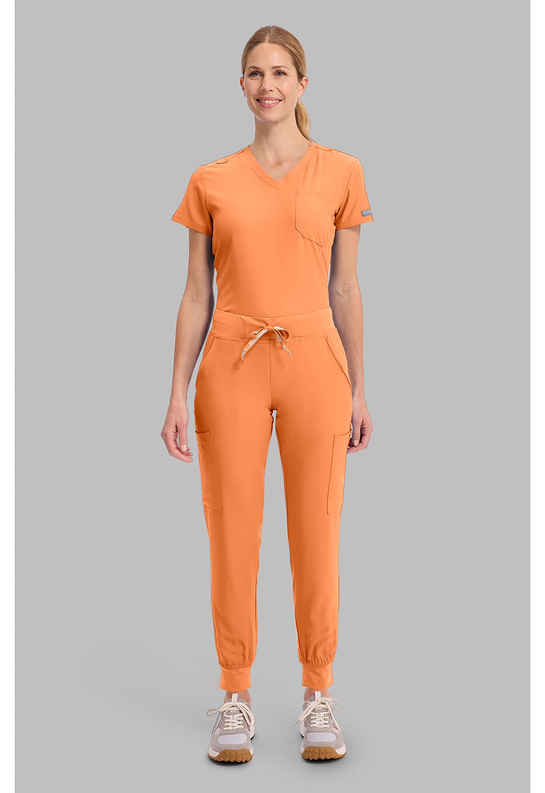 Insight 6-Pocket Scrub Jogger in orange worn by a model with six pockets and jogger cuffs from MED COUTURE Insight for women's scrub workwear